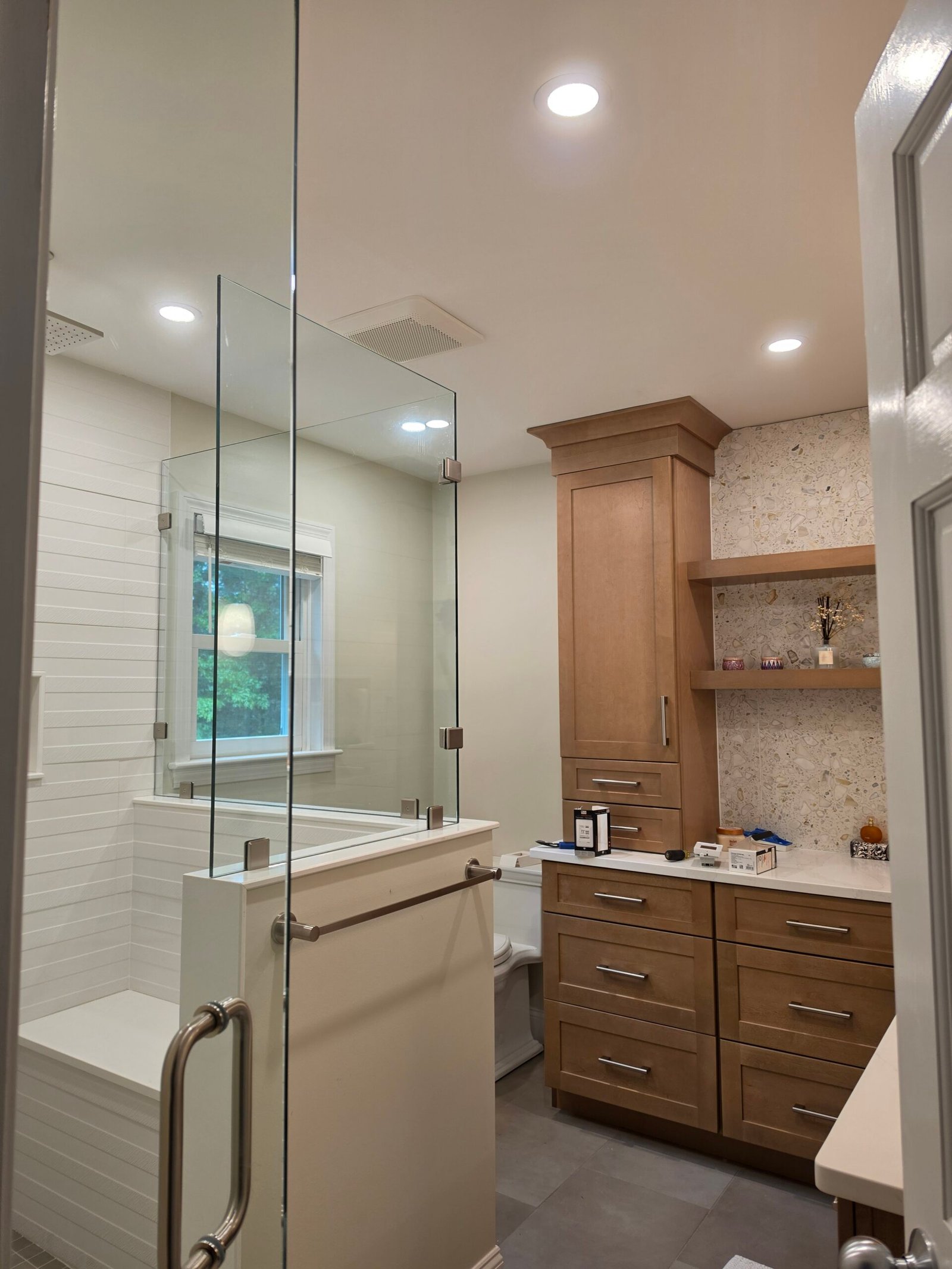 Recessed ceiling lights, fan, and outlet installed in a remodeled residential bathroom