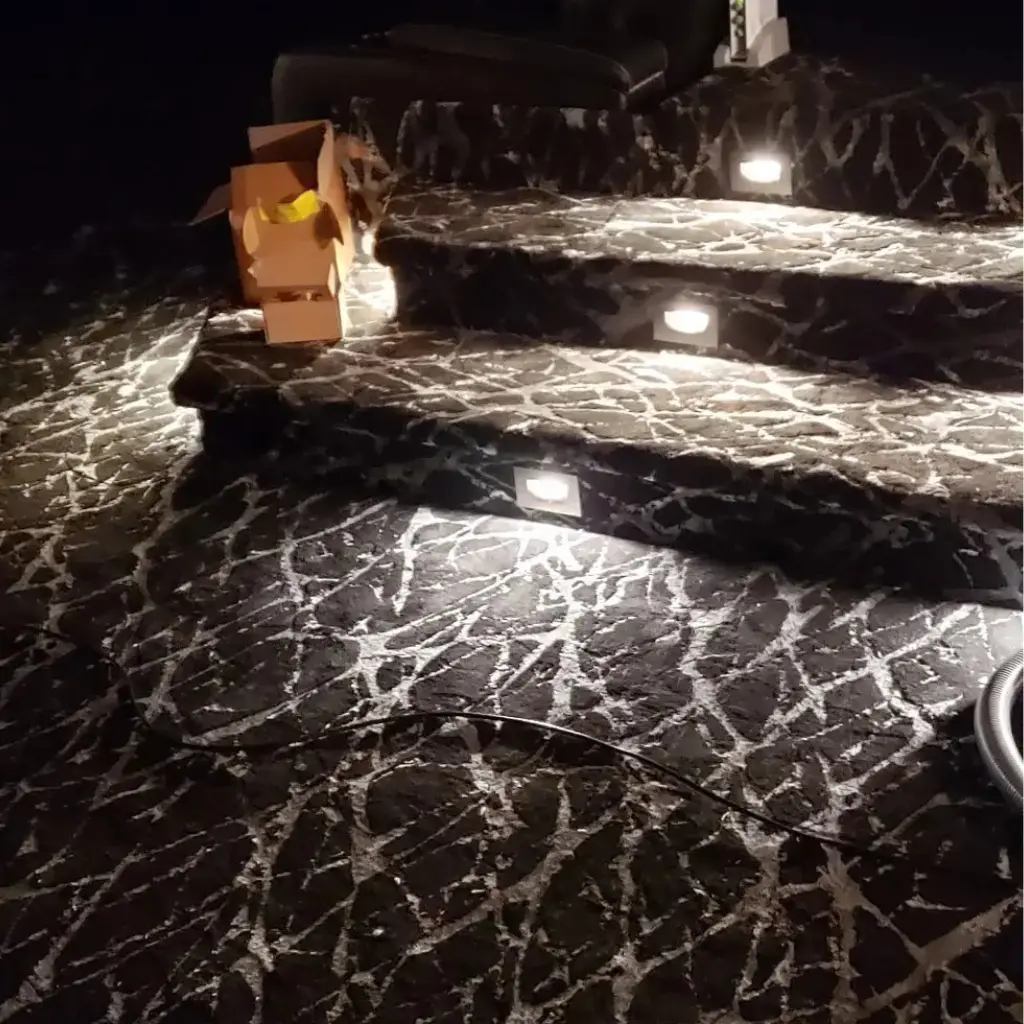 Finished step lights illuminating carpeted stairs inside a residential home theater