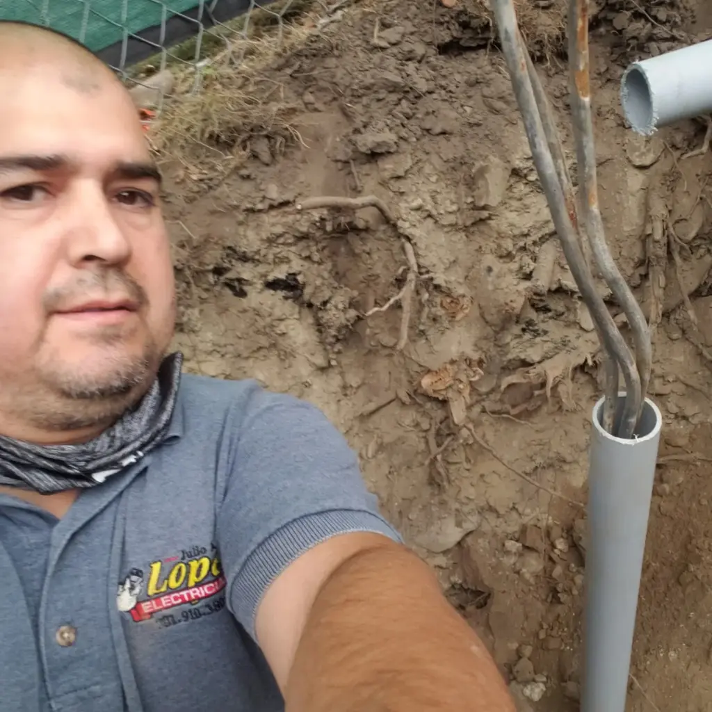 Electrician beside underground conduit carrying electrical service cables during installation