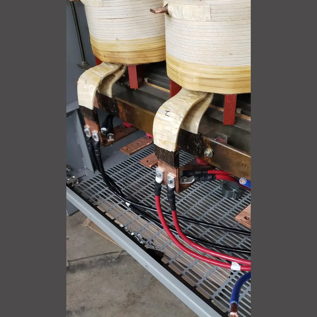 Close-up of industrial transformer coils, copper connections, and heavy electrical cables