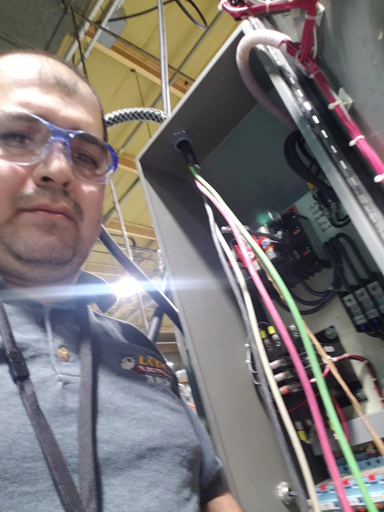 Electrician inspecting wiring inside an open commercial electrical control panel