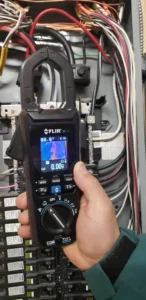 FLIR thermal imaging clamp meter checking wiring temperatures inside an electrical panel