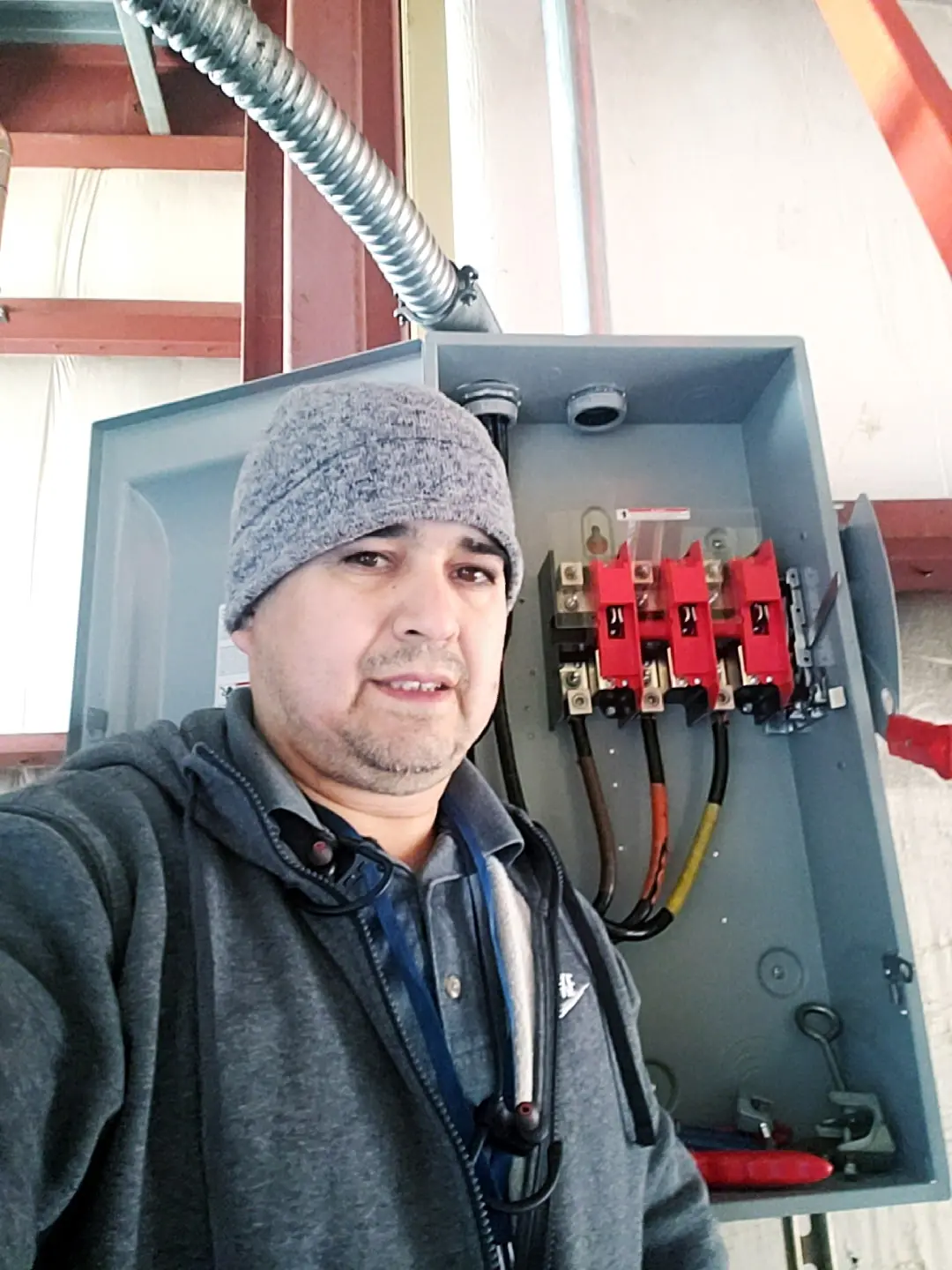 Electrician standing beside an open commercial electrical disconnect during installation