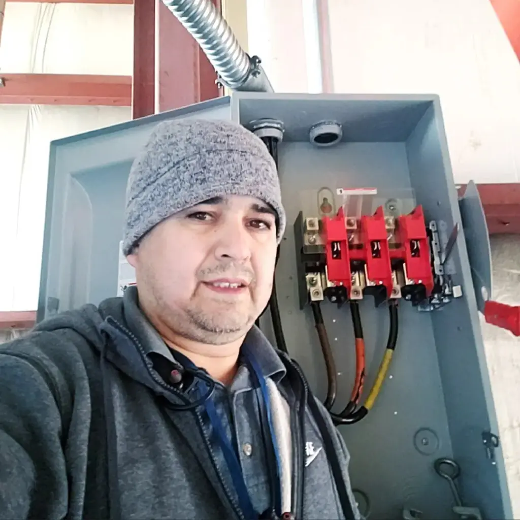 Electrician standing beside an open commercial electrical disconnect during installation