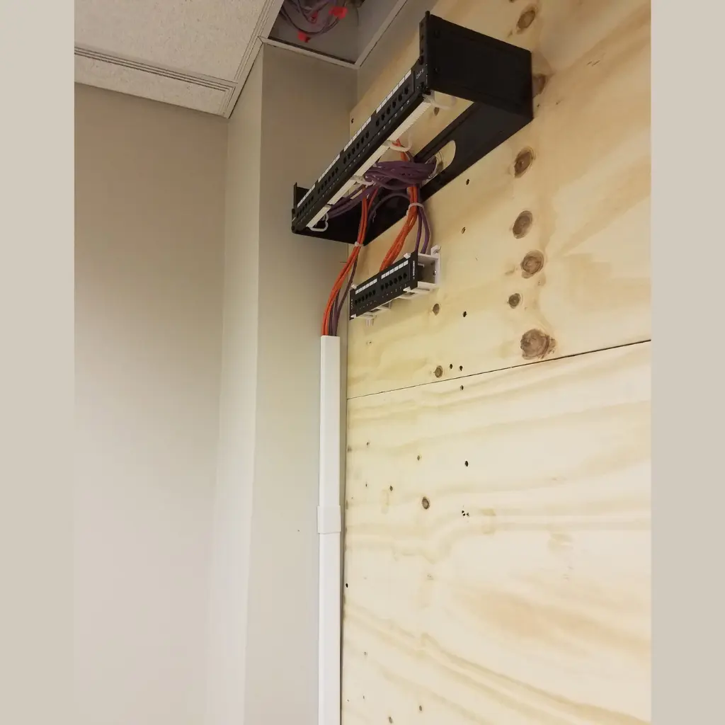 Wall-mounted network patch panels with organized Ethernet cabling and cable raceway