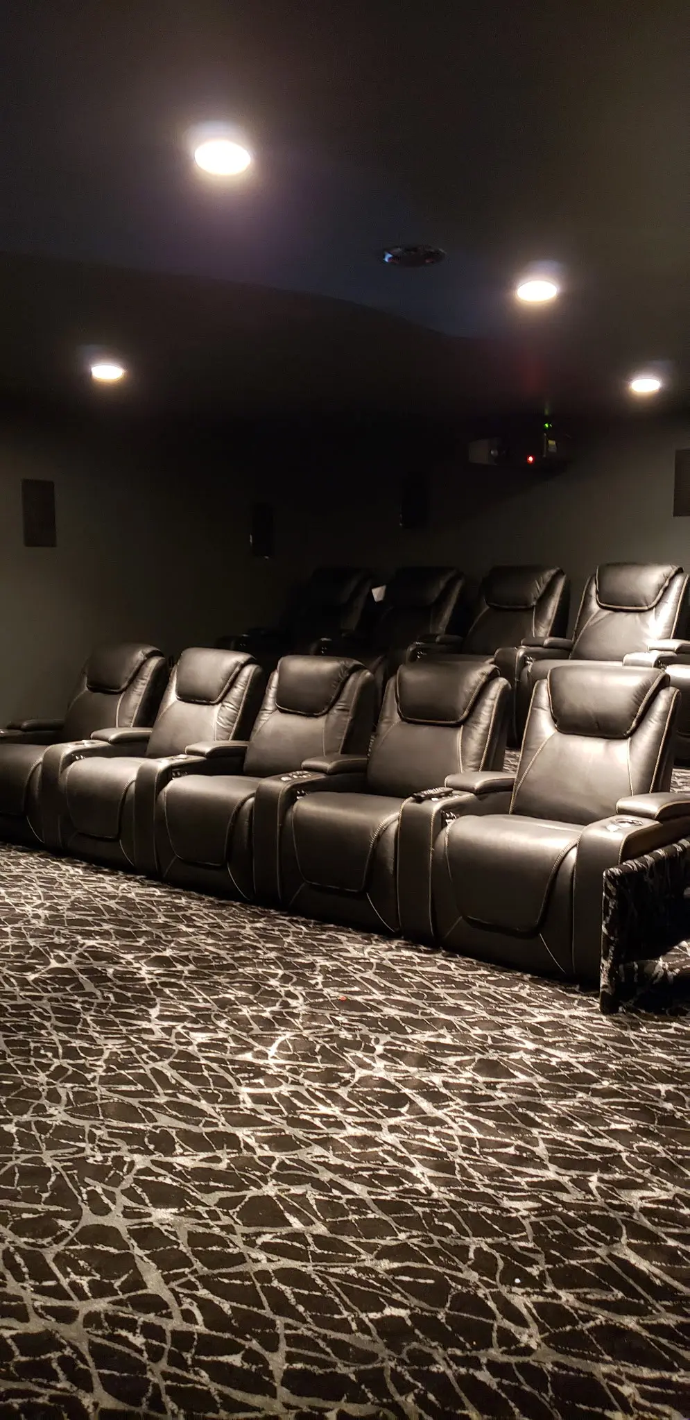 Finished home theater with recessed ceiling lighting above three rows of seating